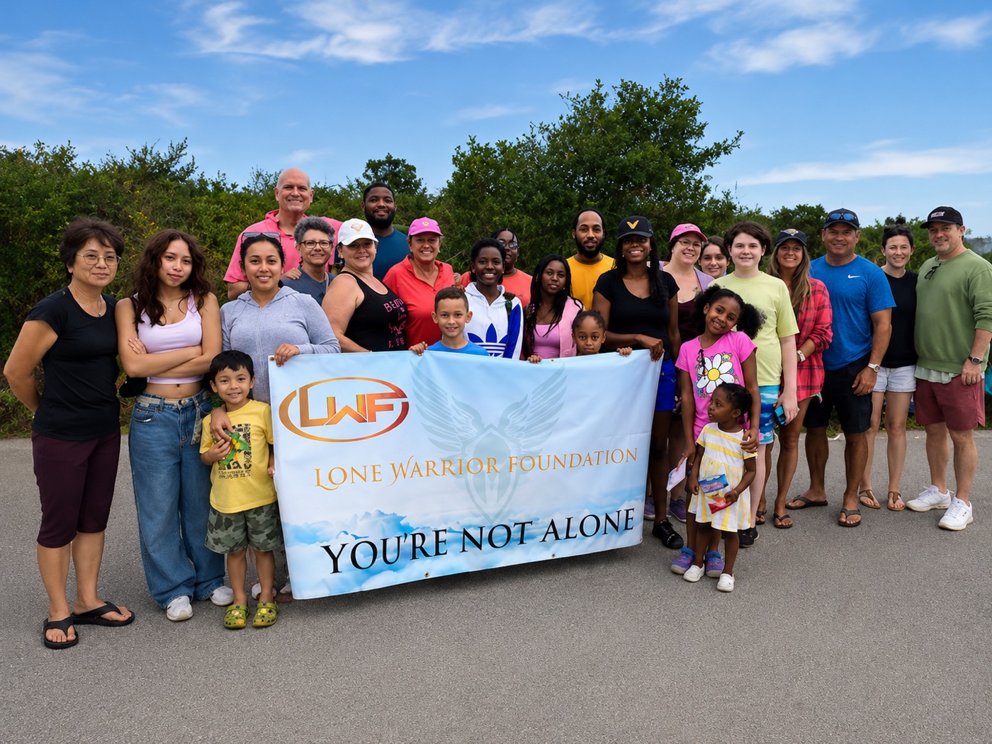 Lone Warrior Foundation families and volunteers together holding the "You're Not Alone" banner